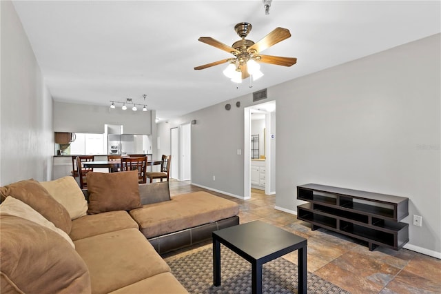 living area featuring a ceiling fan, visible vents, and baseboards