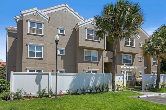 exterior space featuring fence, a lawn, and stucco siding