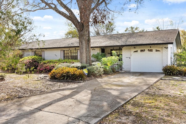 ranch-style home with a garage, concrete driveway, brick siding, and roof with shingles