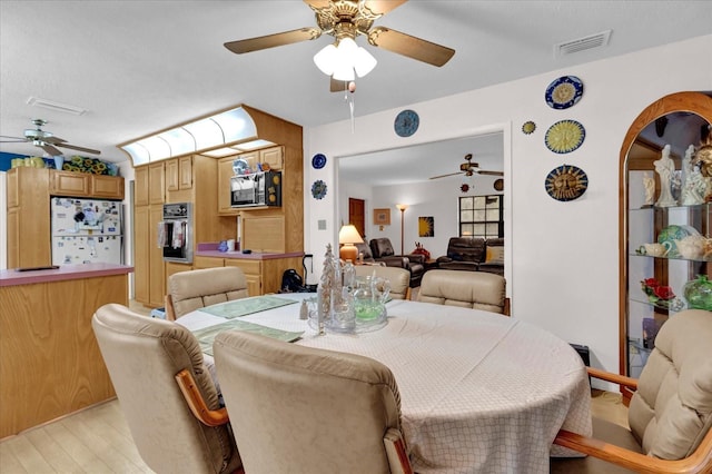 dining area with a ceiling fan, arched walkways, visible vents, and light wood finished floors