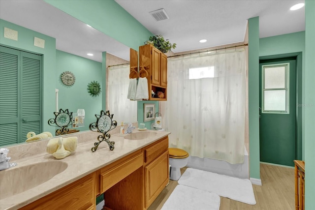 bathroom with toilet, double vanity, a sink, and visible vents