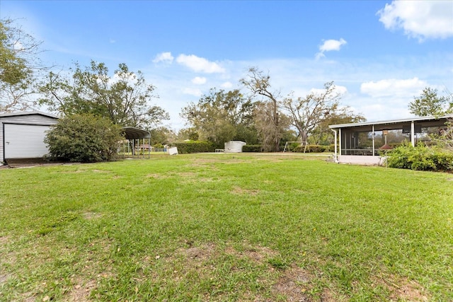 view of yard with an outbuilding, a sunroom, a storage shed, and a detached carport