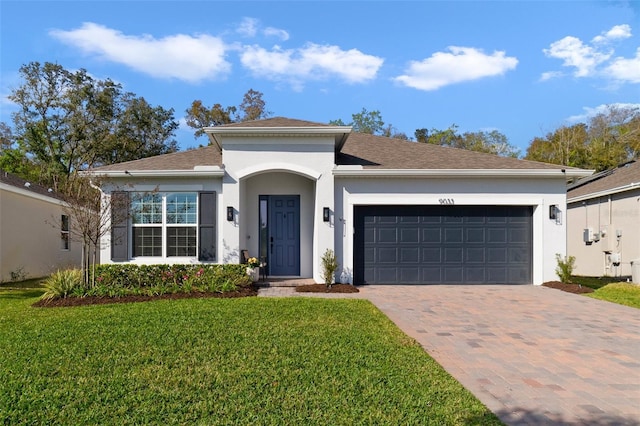 view of front of property with decorative driveway, an attached garage, a front yard, and stucco siding