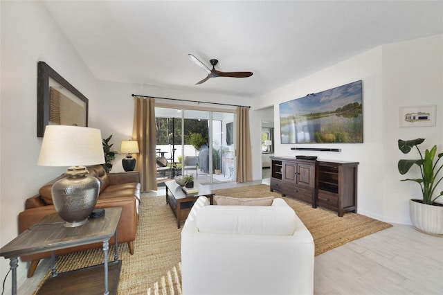 living room featuring light wood-type flooring, ceiling fan, and baseboards