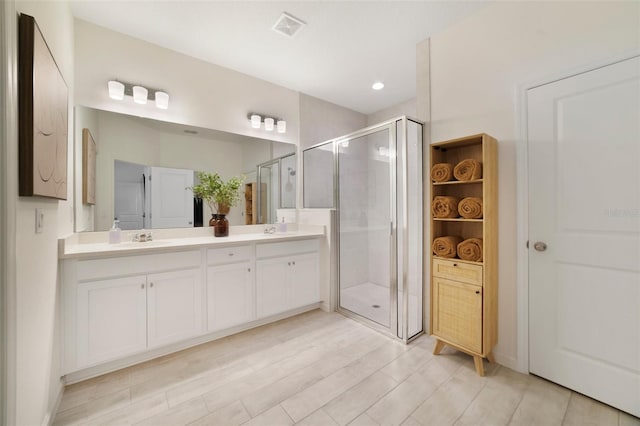 full bathroom with double vanity, a sink, visible vents, and a shower stall