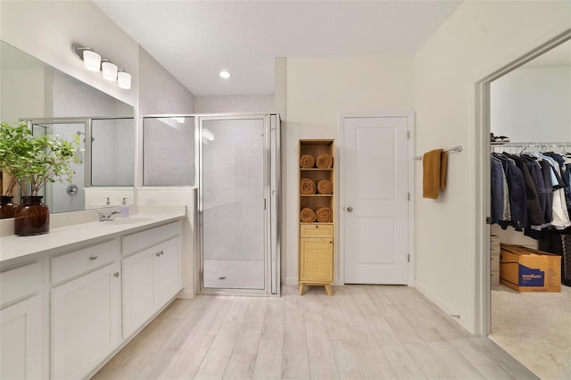 bathroom featuring a stall shower, baseboards, a walk in closet, and vanity