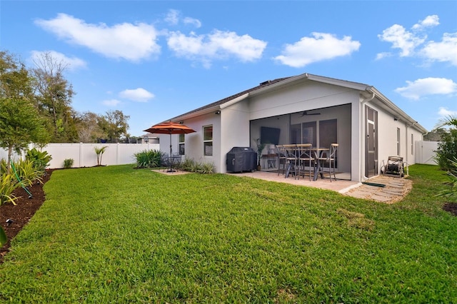 rear view of property featuring a yard, a patio, stucco siding, ceiling fan, and a fenced backyard