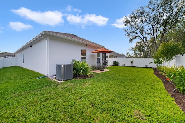 rear view of property featuring stucco siding, a fenced backyard, a lawn, and central AC unit