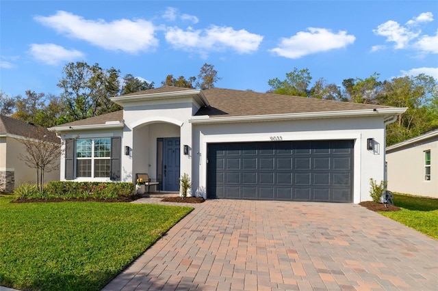 single story home with a garage, decorative driveway, a front lawn, and stucco siding