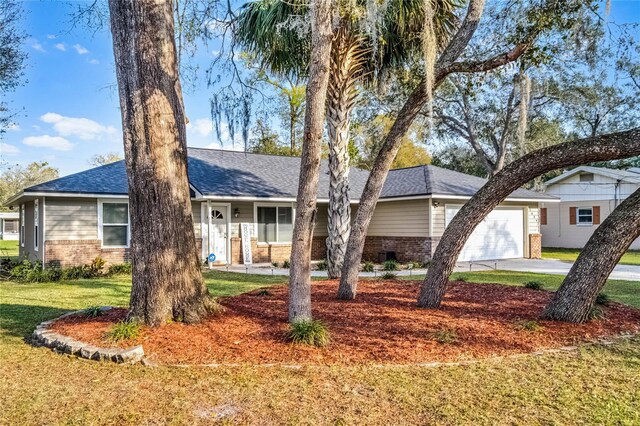 ranch-style home with a garage, a front yard, brick siding, and roof with shingles