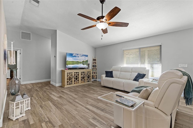 living area featuring lofted ceiling, visible vents, and wood finished floors