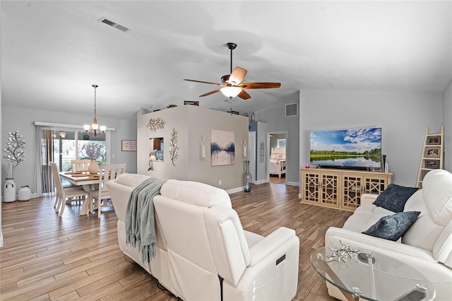 living room featuring ceiling fan with notable chandelier, light wood finished floors, and visible vents