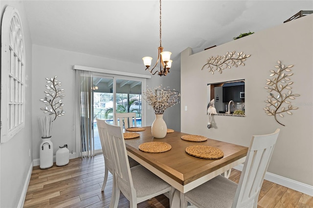 dining area with a chandelier, baseboards, and light wood-style floors