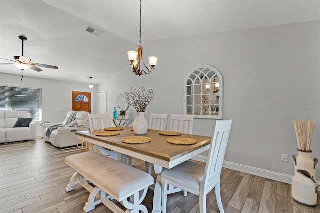 dining room with baseboards, visible vents, light wood finished floors, and ceiling fan with notable chandelier