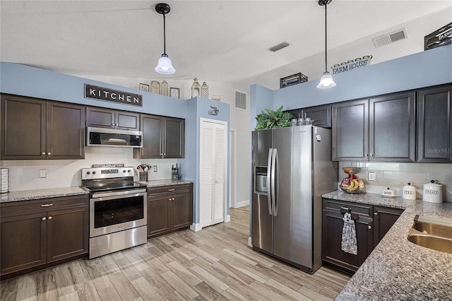 kitchen with appliances with stainless steel finishes, visible vents, and decorative light fixtures