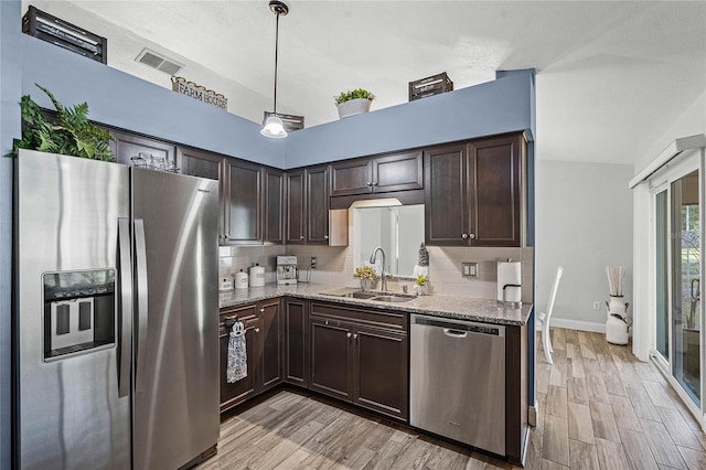 kitchen with dark brown cabinetry, decorative backsplash, stainless steel appliances, and a sink