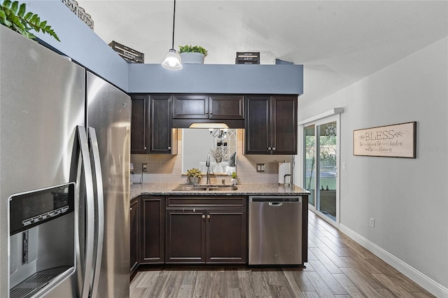 kitchen featuring dark brown cabinetry, a sink, appliances with stainless steel finishes, light wood-type flooring, and decorative backsplash