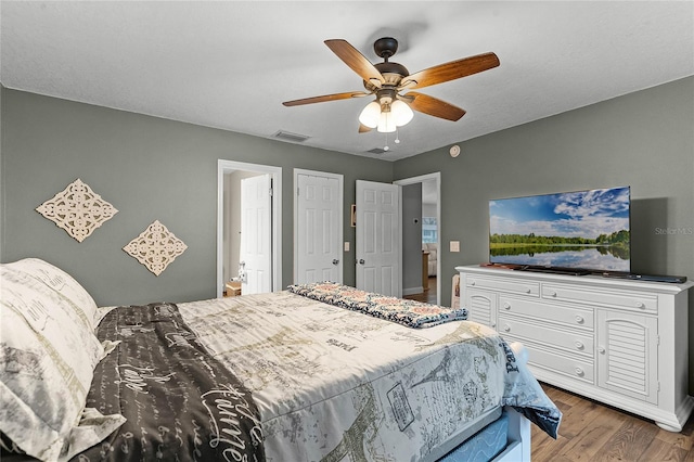 bedroom with ceiling fan, visible vents, and wood finished floors