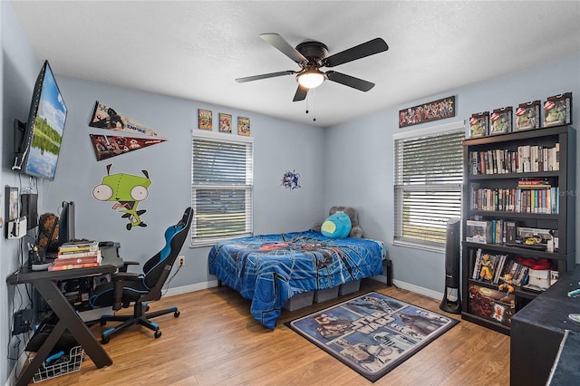 bedroom with multiple windows, wood finished floors, and baseboards