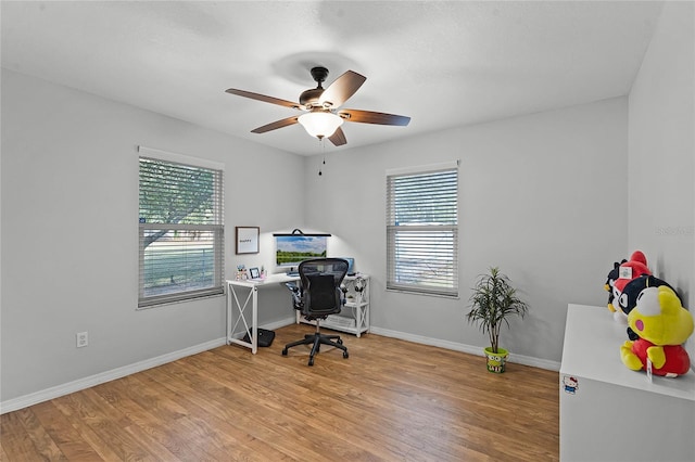 office space with ceiling fan, plenty of natural light, wood finished floors, and baseboards