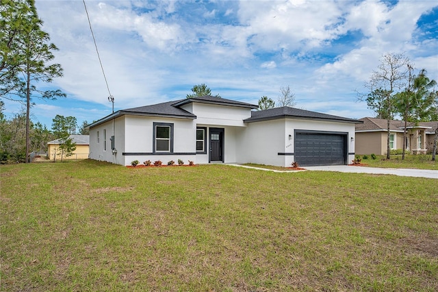 prairie-style house featuring a garage, concrete driveway, a front yard, and stucco siding