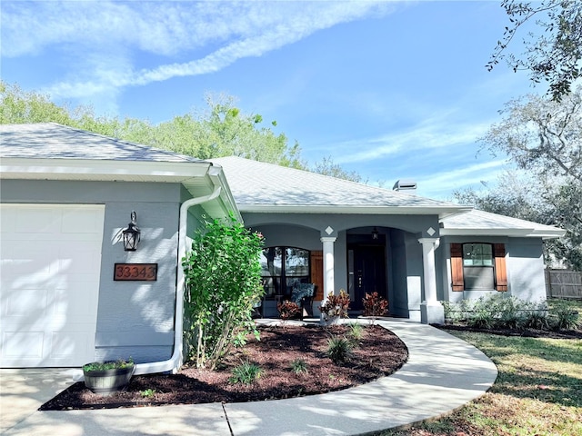 doorway to property with a garage, roof with shingles, and stucco siding