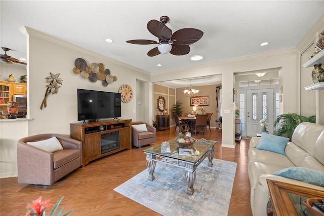 living room featuring crown molding, wood finished floors, and ceiling fan with notable chandelier