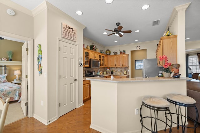 kitchen featuring a peninsula, visible vents, light wood-style floors, appliances with stainless steel finishes, and crown molding