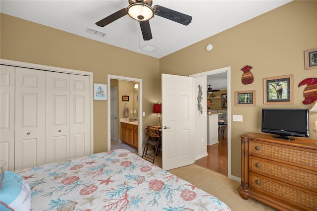 bedroom featuring lofted ceiling, a closet, light colored carpet, visible vents, and a ceiling fan