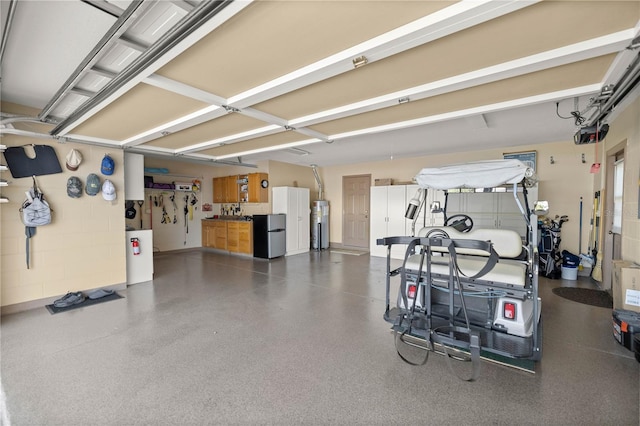 garage with concrete block wall, water heater, and freestanding refrigerator