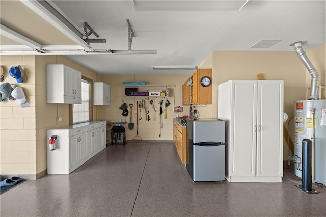 garage with gas water heater, freestanding refrigerator, and concrete block wall