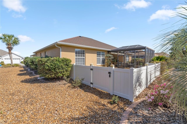 back of house featuring fence private yard, a gate, a lanai, and stucco siding