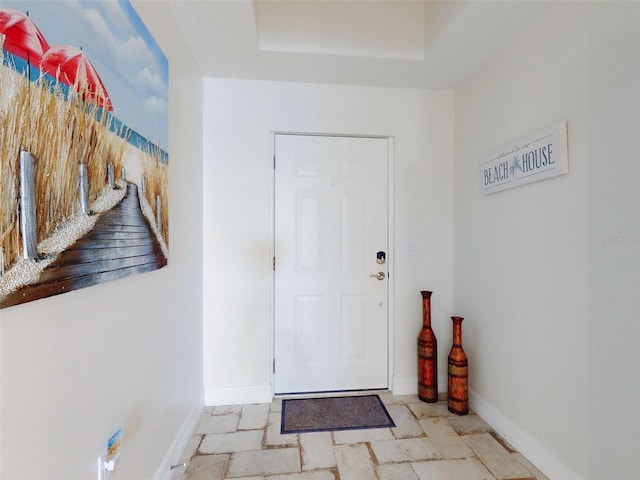 doorway with stone tile flooring and baseboards