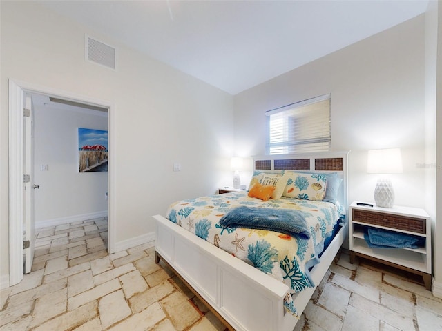 bedroom featuring baseboards, visible vents, and stone tile floors