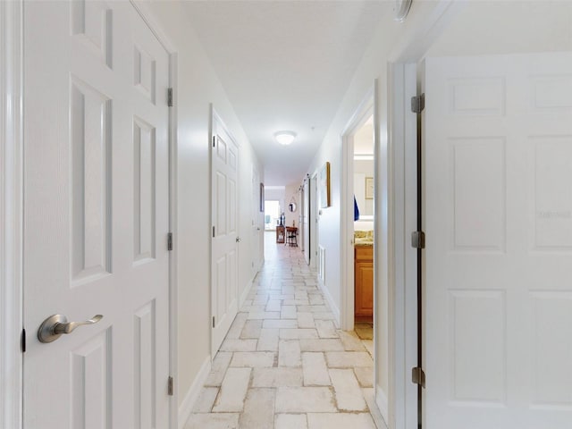 corridor with stone finish floor and baseboards