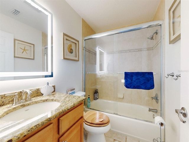 bathroom featuring enclosed tub / shower combo, visible vents, vanity, and toilet