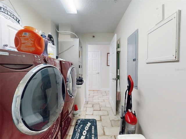 laundry room featuring stone tile floors, washing machine and clothes dryer, a textured ceiling, laundry area, and baseboards