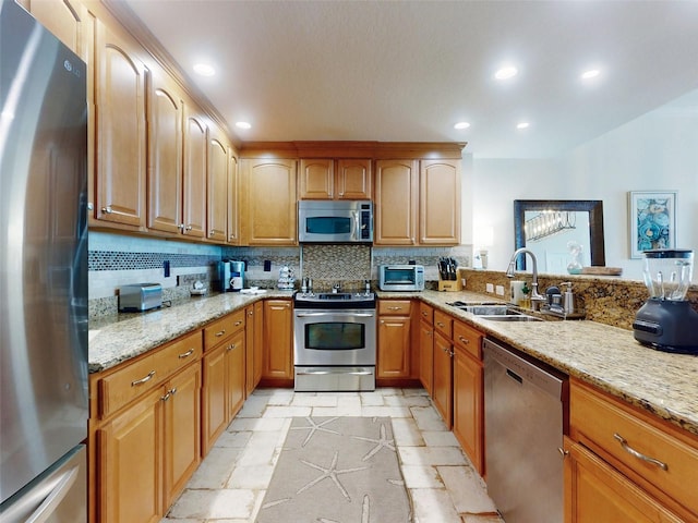 kitchen with light stone counters, stainless steel appliances, stone tile flooring, backsplash, and a sink