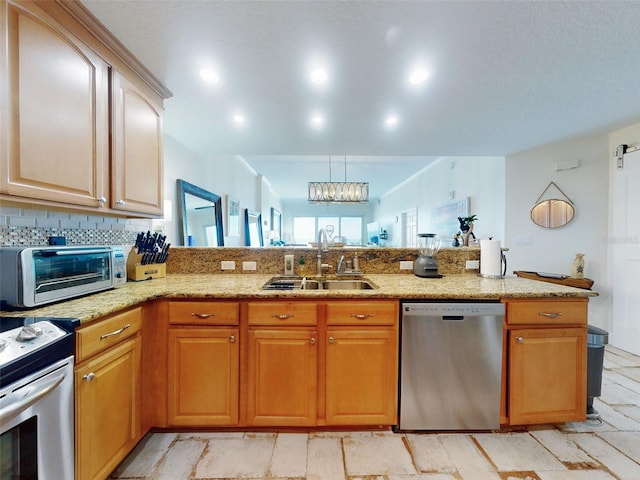 kitchen with light stone counters, a toaster, stainless steel appliances, a sink, and a peninsula