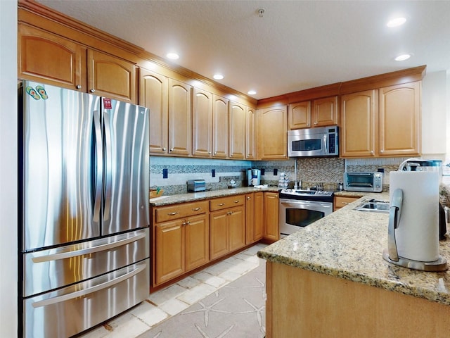 kitchen featuring stainless steel appliances, light stone counters, and decorative backsplash