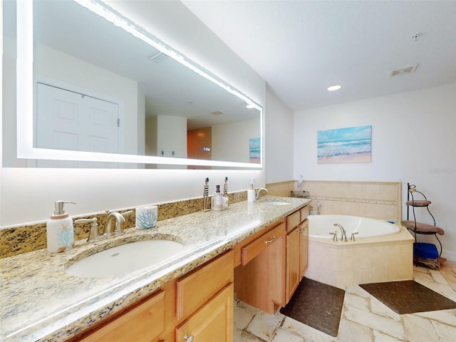 bathroom with a bath, double vanity, visible vents, and a sink