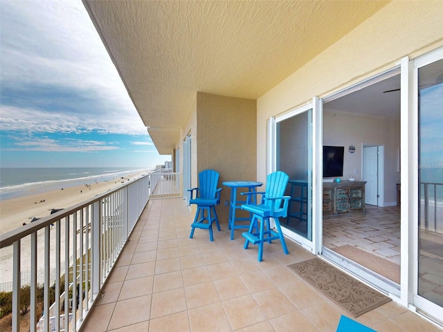 balcony with a water view and a view of the beach