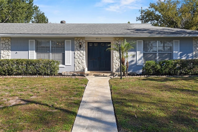 view of front facade with roof with shingles and a front lawn