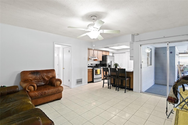 living room featuring a ceiling fan, visible vents, a textured ceiling, and light tile patterned flooring