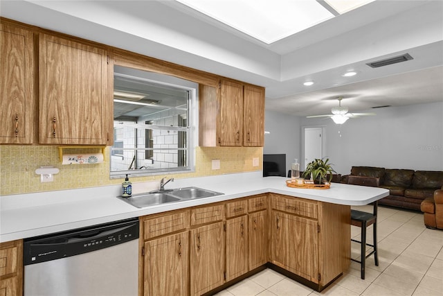 kitchen featuring a peninsula, a sink, visible vents, dishwasher, and a kitchen bar