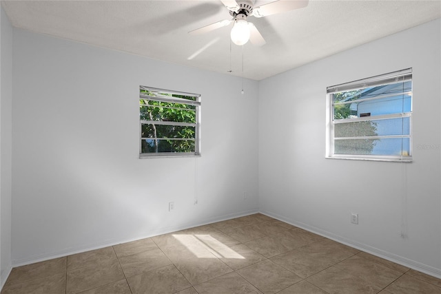 empty room with tile patterned floors, a ceiling fan, and baseboards