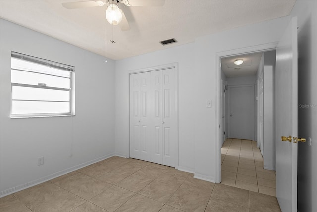 unfurnished bedroom featuring light tile patterned floors, a closet, visible vents, ceiling fan, and baseboards