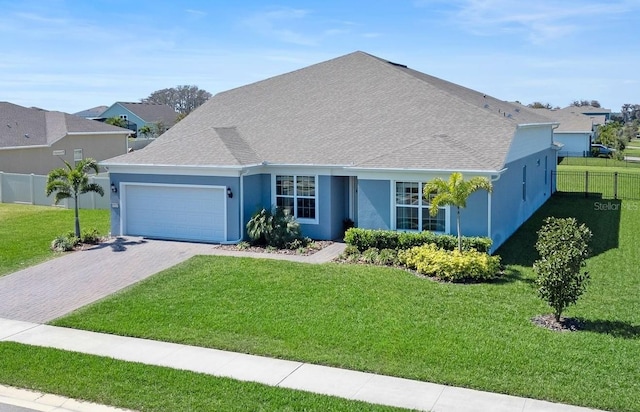 ranch-style house with a garage, fence, decorative driveway, a front yard, and stucco siding