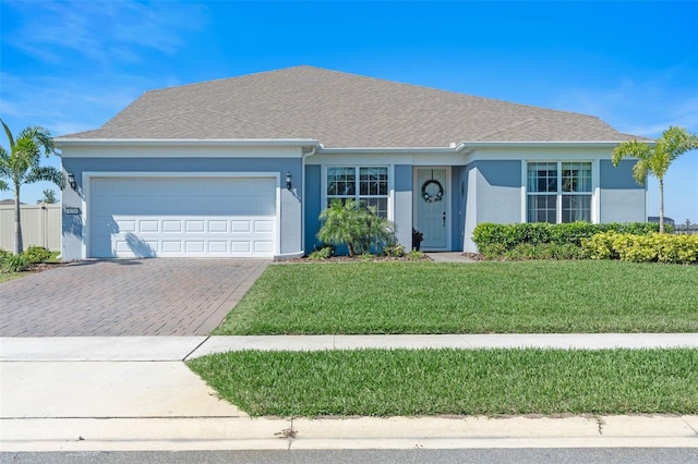 ranch-style home with decorative driveway, roof with shingles, stucco siding, an attached garage, and a front yard