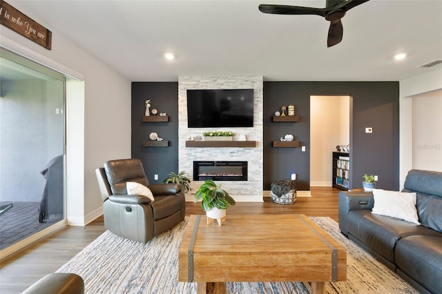 living room with visible vents, a large fireplace, ceiling fan, wood finished floors, and baseboards